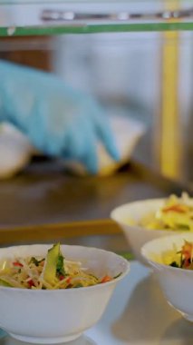 Yemek pişirmek. Yakın plan. Garson, koruyucu eldivenlerle, salata kaselerini self-servis yemek vitrinine koyuyor. Mutfak kafeteryasında açık büfe yemek. Sağlıklı yemek. Gönüllü olmak ve yardım. Yeniden açılıyor. güvenlik kavramı.