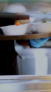 Yemek pişirmek. Yakın plan. Garson, koruyucu eldivenlerle, salata kaselerini self-servis yemek vitrinine koyuyor. Mutfak kafeteryasında açık büfe yemek. Sağlıklı yemek. Gönüllü olmak ve yardım. Yeniden açılıyor. güvenlik kavramı.