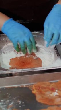 Yemek pişirmek. Yakın plan. Şef, koruyucu eldivenlerle, un içinde çiğ tavuk pirzolası ve çırpılmış çiğ yumurta pişirir, sonra da tavada pişirir. Sağlıklı yemek. Gönüllü olmak ve yardım. Yeniden açılıyor. güvenlik kavramı.