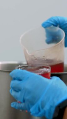 Yemek pişirmek. Yakın plan. Aşçı, koruyucu eldivenlerle, demlenmiş meyve suyu, büyük demlikten bardaklara meyve suyu döker. Sağlıklı yemek. Gönüllü olmak ve yardım. Yeniden açılıyor. güvenlik kavramı.