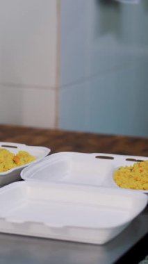 Yemek pişirmek. Yakın plan Gönüllü, koruyucu eldivenler giyip fakir insanlara ulaştırılmak üzere beslenme çantalarına bedava sıcak yemek koyun. Yemek servisi. Yardım projesi, bağış yardımı,