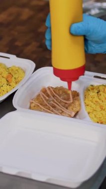 Yemek pişirmek. Yakın plan Gönüllü, koruyucu eldivenler giyip fakir insanlara ulaştırılmak üzere beslenme çantalarına bedava sıcak yemek koyun. Yemek servisi. Yardım projesi, bağış yardımı,