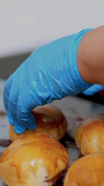 Yemek pişirmek. Fırın. Yakın plan. Fırıncı koruyucu eldivenlerle fırından yeni çıkmış hamur işlerini kaldırıyor. Sağlıklı yemek. Covid-19 'dan sonra tekrar açılıyor. Güvenlik kavramı. Gönüllülük ve yardım.