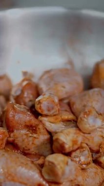 Yakın plan. Mutfak işçisi, koruyucu eldivenler giymiş, pişirmeden önce baharatlı sosla çiğ tavuk bacağı karıştırıyor. Sağlıklı yemek. Gönüllü olmak ve yardım. Covid-19 'dan sonra tekrar açılıyor. güvenlik kavramı.