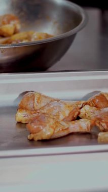 Yakın plan. Mutfak işçisi, koruyucu eldivenlerle, fırında pişirmek için çiğ tavuk bacağı serer. Sağlıklı yemek. Gönüllü olmak ve yardım. Covid-19 'dan sonra tekrar açılıyor. güvenlik kavramı.