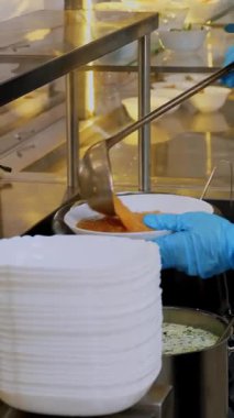 Yakın plan. Garson, koruyucu eldivenlerle, tabağa çorba koyar ve self servis kafeteryasında ya da açık büfede müşterilere servis yapar. Covid-19 'dan sonra tekrar açılıyor. Güvenlik kavramı. sağlıklı gıda.