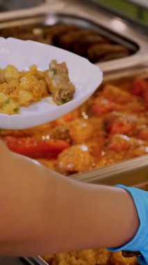 Yemek pişirmek. Yakın plan. Garson, koruyucu eldivenlerle, self-servis kafeteryasında ya da açık büfede müşterilere yemek hazırlıyor. Covid-19 'dan sonra tekrar açılıyor. Güvenlik kavramı. sağlıklı gıda.