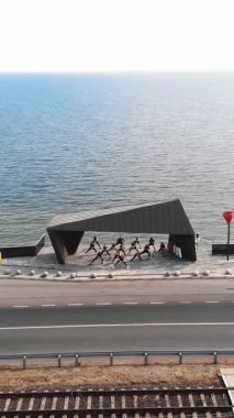 CHERKASSY, UKRAINE, 24 EYLÜL 2020: açık havada grup fitness eğitimi. Genç sporcular spor için barajdaki gözlem güvertesine nehrin panoramik manzarasıyla gidiyorlar. Spor Kulübü. Havadan çekim. Refah yaşam tarzı konsepti