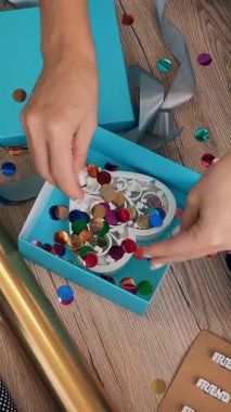 Hediyeler yakın çekimde paketleniyor. Üst Manzara. Hediye ve dekorasyon tasarımcısı bir hediye kutusu hazırlar, dizüstü bilgisayarın önüne ipek kurdeleyle fiyonk bağlar. video günlüğü, webinar.