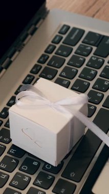 Hediyeler yakın çekimde paketleniyor. Dizüstü bilgisayarda küçük bir kutu. Laptop klavyesinde fiyonklu hediye kutusu var. İnternet alışveriş konsepti. çevrimiçi satış