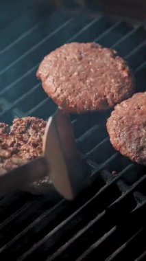 Aşçılık. Hamburger pişirmek. Yakın plan. Restoranın mutfağında, Brezilya usulü, sıcak barbekü ızgarasında hamburgerler için taze et pirzolası pişirme işlemi. Fast food, abur cubur