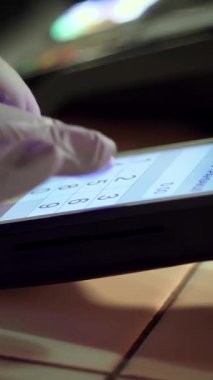 NFC teknolojisi. Yakın plan. Garson, koruyucu eldivenlerle parmak izleri, temas kurulamayan ödemeler için terminale gidiyor. Elektronik ödeme makinesinden ya da kart okuyucudan telefonla ödeme yapmak. Cep telefonu, kablosuz ödeme