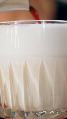 Bardakta latte. Yakın plan, barista latte yapar, nazikçe köpüklü süte kahve ekler, güzel bir bardakta..