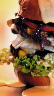 Hamburger, hamburger. Yakın plan. Tahta tepside, sulu, lezzetli, taze hazırlanmış, patates ve soslu yağlı bir burger. Fast food, abur cubur