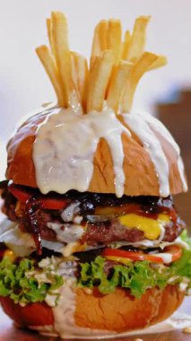 Hamburger, hamburger. Yakın plan. Tahta tepside, sulu, lezzetli, taze hazırlanmış, patates ve soslu yağlı bir burger. Fast food, abur cubur