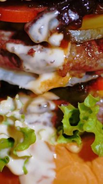 Hamburger, hamburger. Yakın plan. Tahta tepside, sulu, lezzetli, taze hazırlanmış, patates ve soslu yağlı bir burger. Fast food, abur cubur.