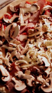 Aşçılık. Pizza yapmak. Yakın çekim, üst görüş. Et ve mantarlı pizza hamuru. Şef üzerine rendelenmiş peynir serpiyor. İtalyan pizzası pişirme süreci .