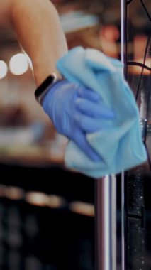 Yakın plan. Garson, koruyucu eldivenler, temizlik, restoran giriş kapısını silme antiseptik sprey ve peçete kullanma. pandemik koronavirüs.