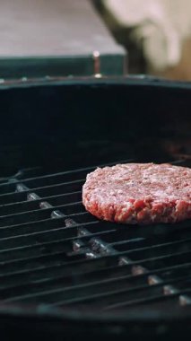 Aşçılık. Hamburger pişirmek. Yakın plan. Restoranın mutfağında, Brezilya usulü, sıcak barbekü ızgarasında hamburgerler için taze et pirzolası pişirme işlemi. Fast food, abur cubur