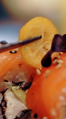Geleneksel Japon yemekleri. Yakın plan. Suşi şefi taze pişmiş suşi rulolarını küçük limonlarla süslüyor. Japon yemek gurmesi. sanat restoranda hizmet veriyor..