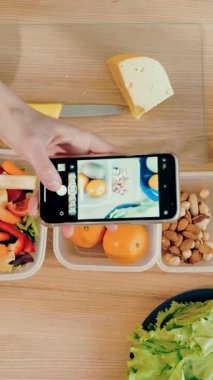 İnternette yemek yapmak. Sağlıklı yemek. Yakın plan. Üst Manzara. Kadın blogcu, sosyal medya için akıllı telefondan ev mutfağında vejetaryen yemeğinin fotoğraflarını çekiyor. Mutfak vlogları, sosyal ağlar.