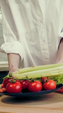 İnternette yemek yapmak. Sağlıklı yemek. Yakın plan. Kadın masaya bir tabak sebze koyar ve cam tahtaya biber doğrar. Mutfak vlogları, sosyal ağlar