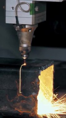 Metal borular için lazer kesme makinesi. Yakın plan. Yan görünüş. CNC fiber lazerli modern makine kare metal boruları kesiyor. Kesme işlemi sırasında lazer ışınından parlak kıvılcımlar uçuşuyor