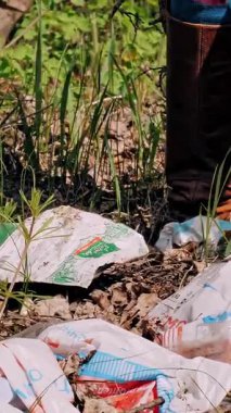 Dışarıdaki çöpler. Yakın plan. Gönüllü, koruyucu eldivenlerle, plastik ve diğer çöpleri topluyor, çöpe atılıyor ve plastik çöp torbasına koyuyor. Dışarıdaki çöpler..