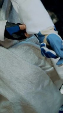 Eskrim. Yakın plan. Düşük fiziksel yetenekleri olan, tekerlekli sandalyede oturan sporcu eskrim antrenmanına hazırlanıyor. Eskrimci özel bir eldiven takar, onu tamir eder, kılıcı sensörlere bağlar.