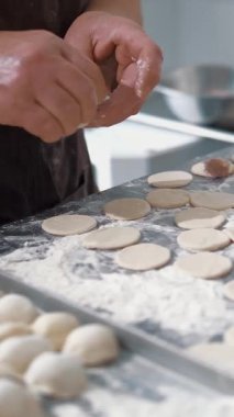 Yarı bitmiş ürünler. Yemek pişirmek. Yakın plan. Aşçının elleri hamur, mantı, ravioli ve pelmeni yapmak için kıyma parçaları serer. Açık büfe restoran mutfağı..