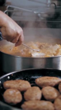 Yemek pişirmek. Açık büfe restoran mutfağı. Yakın plan. Yemek tavada kaynıyor, kaynıyor. Ticari bir mutfakta yemek pişirme işlemi.