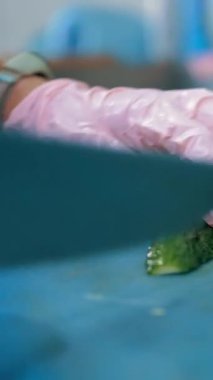 Yemek pişirmek. Şef sebze keser. Açık büfe restoran mutfağı. Yakın plan. Şef, plastik tahta üzerinde keskin, büyük bir mutfak bıçağıyla taze salatalıkları küçük parçalara ayırıyor..