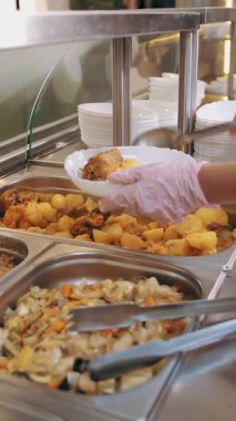 Açık büfe restoranı. Kendi kendine hizmet veren kafeterya. Yakın plan. Garson, koruyucu eldivenlerle, müşteriler için yemek hazırlıyor. Yemek pişirmek. sağlıklı gıda.