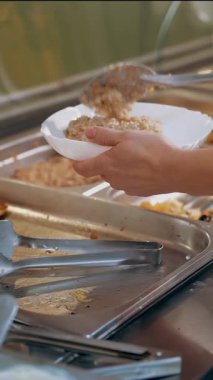 Açık büfe restoranı. Kendi kendine hizmet veren kafeterya. Yakın plan. Garson, koruyucu eldivenlerle, müşteriler için yemek hazırlıyor. Yemek pişirmek. sağlıklı gıda.