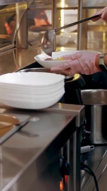 Açık büfe restoranı. Kendi kendine hizmet veren kafeterya. Yakın plan. Garson, koruyucu eldivenlerle müşteriye sıcak çorba dolduruyor. Yemek pişirmek. sağlıklı gıda.