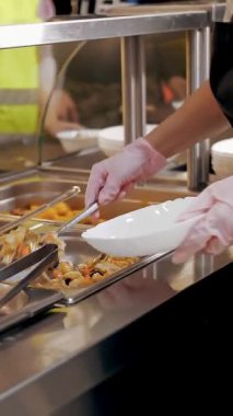 Açık büfe restoranı. Kendi kendine hizmet veren kafeterya. Yakın plan. Garson, koruyucu eldivenlerle, müşteriler için yemek hazırlıyor. Yemek pişirmek. sağlıklı gıda.
