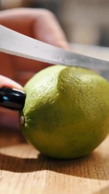 Limonu kes. Yemek pişirmek. Yakın plan. Kadın elleri taze limonu bir bıçakla ikiye böldü, tahta bir kalasta.