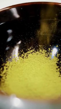 Kibrit. Yakın plan. Küçük siyah bir kasede yeşil kibrit çay tozu. Japon usulü kibrit yeşil çay yapıyorum.