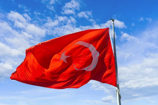 red turkish flag waving against the blue sky