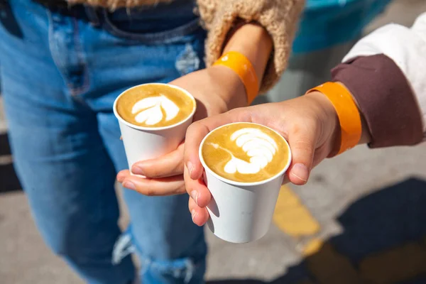 two woman holding coffee cup with latte art