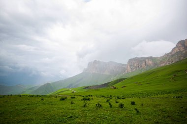 Amazing view of green mountains with clouds and dramatic sky. Majestic mountains and a beautiful green valley surrounded by forested mountains on a rainy spring day.