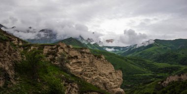 Amazing view of green mountains with clouds and dramatic sky. Majestic mountains and a beautiful green valley surrounded by forested mountains on a rainy spring day.