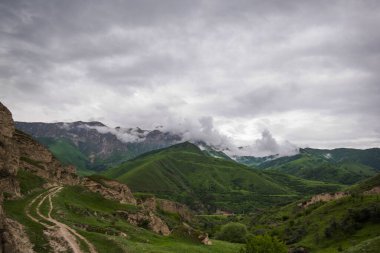 Amazing view of green mountains with clouds and dramatic sky. Majestic mountains and a beautiful green valley surrounded by forested mountains on a rainy spring day.