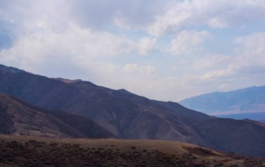 Bulutlu gökyüzü ile inanılmaz bir dağ manzarası. Güzel kırsal kesimin manzarası. Dağlarda harika bir sonbahar. Kuru çayır ve yuvarlanan tepeler. Doğal dış seyahat geçmişi. Güzellik dünyası.