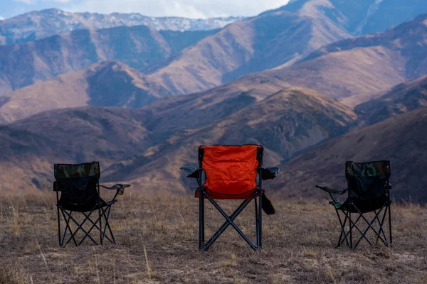 Three empty camping chairs stand on top of a mountain. The perfect place to watch the sunset. Active lifestyle. Autumn in the remote foothills of northern China.