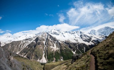 Mountain landscape. Caucasus mountains. Svaneti. Georgia. Panoramic view from the hill on mountains with hiking path against cloudy sky.