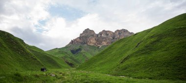 Yaz dağı manzarası. Gürcistan, Kafkasya 'daki vadi manzarası ve yemyeşil otlaklar inanılmaz. Yüksek sıradağlarla çevrili bir vadi. Baharda bulutlu ve yağmurlu bir gün, alçak fırtına bulutları.