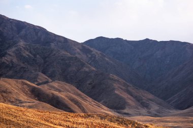 Dağlardan oluşan katmanlar, gölgeleri ve oluşumları ışıkla vurgulanmıştır. Uzak puslu dağlar, batan güneşin farklı gölgeleri..