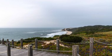 Atlantik Okyanusu 'nu gören görkemli kıyı şeridi. Doğa manzarası sahili. Portekiz, plaja giden tahta yol..