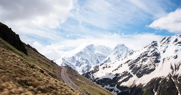 stock image Beautiful mountain peaks in snow. Landscape with high mountains, blue sky with clouds. Nature. Dark scenery. Bright white snowy peaks above the autumn plateau. Autumn in the mountains.